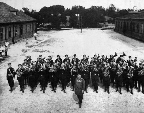 Orchestra of the Life Guard 1st Rifle Battalion. In the background: a building of the wooden barracks of the regiment. Tsarskoye Selo. 1907-1908. The Central State Archive of Cinema, Photography and Phono  Documents.